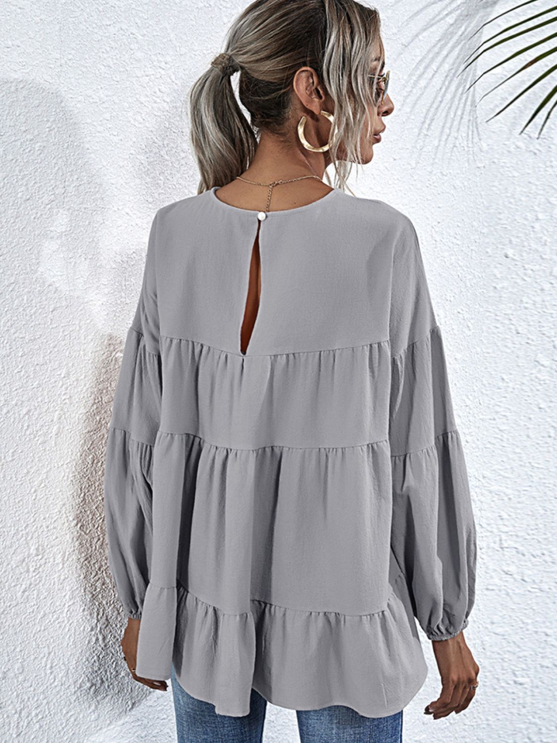 Shiny round neck dropped shoulder tiered blouse by BELLA, featuring a stylish design with layered fabric and a glossy finish.