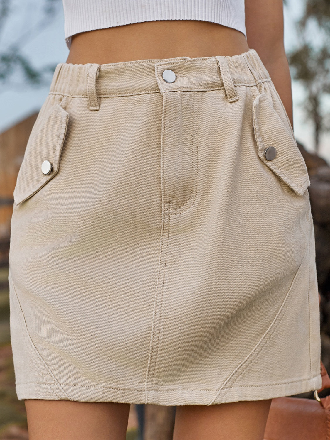 BELLA trendsi pocketed buttoned mini denim skirt displayed on a hanger, featuring a high waist and classic blue denim fabric.