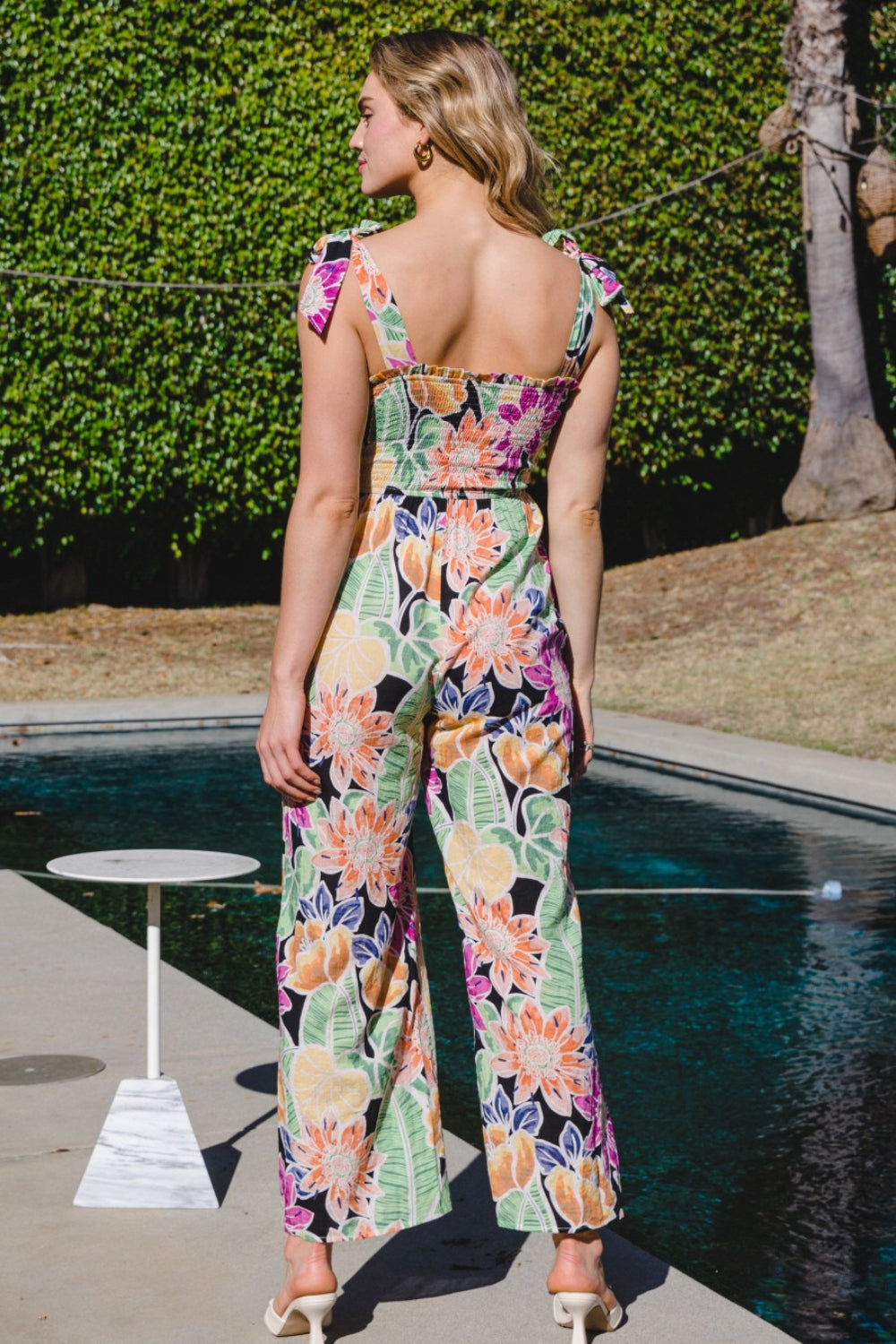 Full size floral sleeveless wide-leg jumpsuit by BELLA in vibrant print, displayed on a hanger with a plain background.