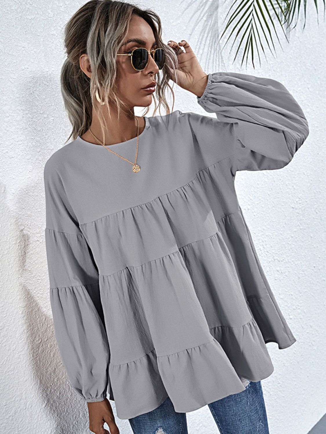 Shiny BELLA tiered blouse with round neckline and dropped shoulders, featuring a stylish, flowy design.